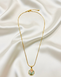 Gold necklace with a floral pendant on a white fabric background